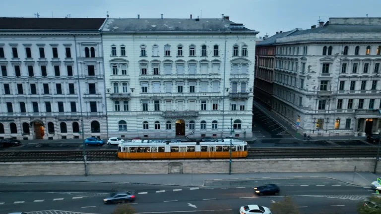 Budapests Straßenbahn fährt in der blauen Stunde an historischen Wohngebäuden vorbei