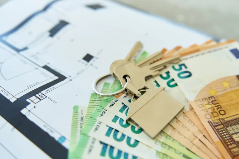 Investitionen in Immobilien erklärt: Wie sie Geld verdienen, welche Kosten und Risiken sie mit sich bringen Schlüssel zu einem Haus und Euro-Banknoten auf einem architektonischen Grundriss